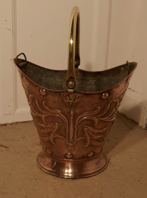 An Art Nouveau Embossed Copper Helmet Coal Scuttle with Liner