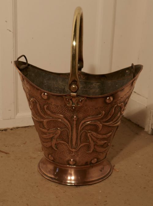 An Art Nouveau Embossed Copper Helmet Coal Scuttle with Liner