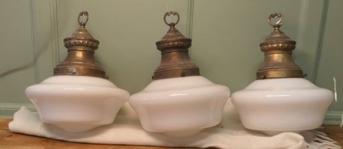 fig 1. A set of four industrial ceiling lights with white opaline glass shades and patinated brass galleries featuring molded top collars and hanging rings.