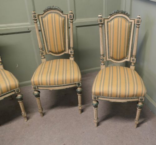 fig 1. A set of four antique French salon chairs featuring carved cream and green painted frames with yellow and cream striped fabric upholstery.