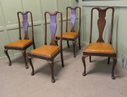 fig 1. A set of four dark oak dining chairs with high vase-splat backs, tan leather drop-in seats, and front cabriole legs ending in pad feet.