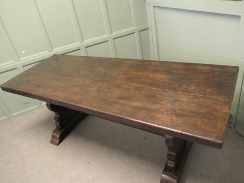 fig 1. A solid dark oak French country refectory table featuring a thick rectangular top supported by twin trestle legs connected with a low central stretcher.