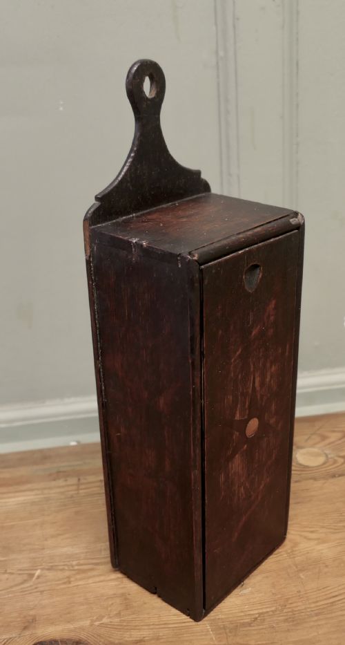 fig 1. An 18th-century dark oak wall-hanging candle box featuring a shaped backboard and a sliding front panel carved with a star motif.