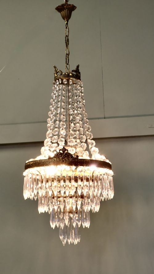 fig 1. A French Empire style crystal waterfall chandelier featuring a central gilt brass band with tiered crystal drops and upper octagonal crystal bead strands.