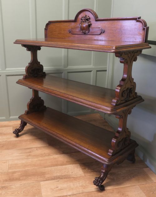 fig 1. A three-tiered late Victorian carved oak buffet featuring an architectural gallery back with central carved cresting, open shelves, carved scroll supports, and castor feet.