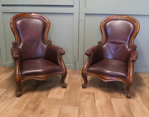 fig 1. A pair of Victorian spoon back armchairs with carved mahogany frames, deep brown leather upholstery, and cabriole front legs.