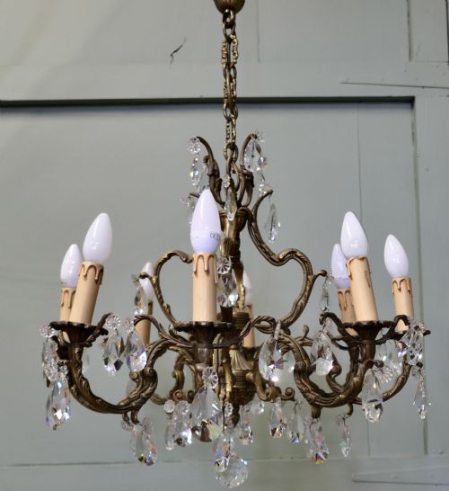 fig 1. An ornate multi-arm French brass chandelier fitted with candle-effect bulbs and decorated with faceted crystal drop lustres.