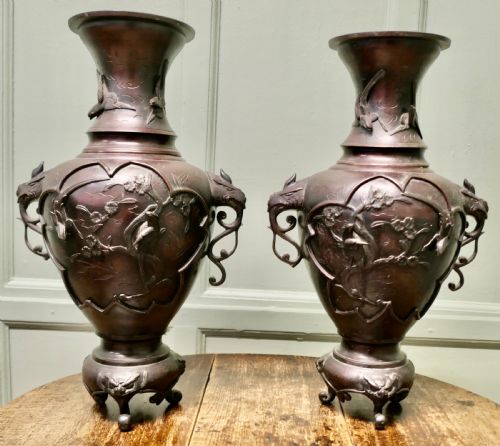 fig 1. A pair of dark brown Japanese Meiji period bronze vases featuring relief depictions of birds on branches and dragon-shaped handles on footed bases.