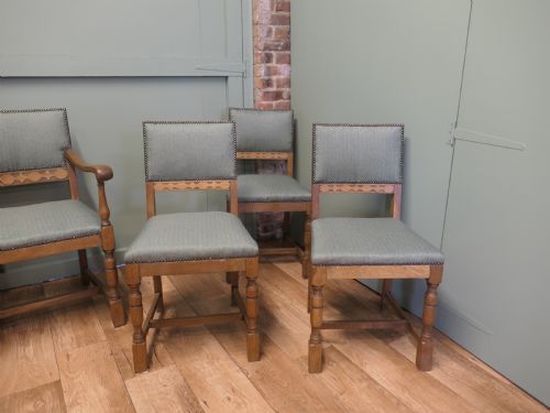 fig 1. A set of eight Arts and Crafts golden oak dining chairs with upholstered seats and backrests trimmed with brass studs.