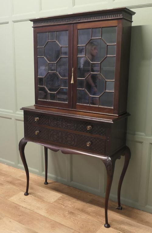 fig 1. A mahogany Chinese Chippendale display cabinet featuring geometric astragal glazed doors, carved fretwork drawer fronts, and elevated slender cabriole legs.