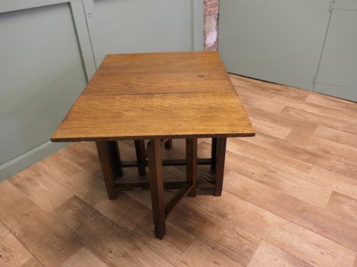 fig 3. An Arts and Crafts golden oak drop-leaf dining table with pierced cutout side panels.