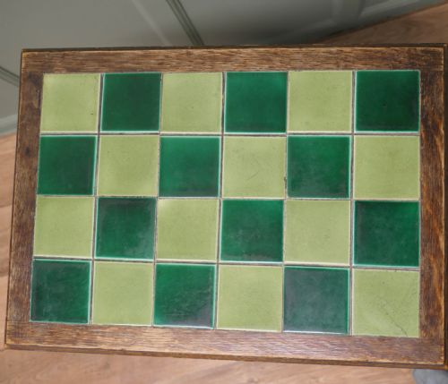 fig 1. An Arts and Crafts oak occasional table featuring a green checkerboard ceramic tiled top, tapered legs, and heart-shaped cutouts on the apron.