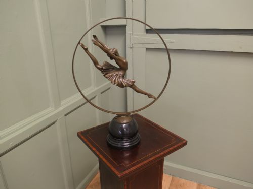 fig 1. A bronze sculpture depicting a ballerina leaping inside a circular hoop, mounted on a turned black marble base.