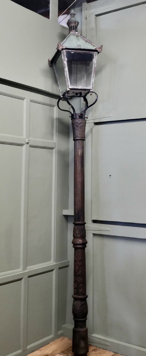 fig 1. A tall Victorian cast iron lamppost featuring an ornate fluted column topped with a four-sided copper lantern with a verdigris patina.