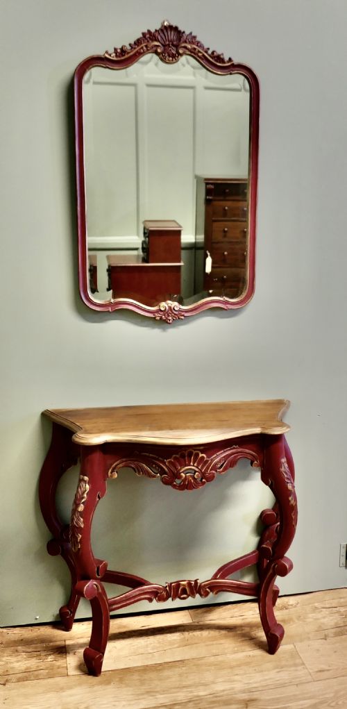 fig 1. A red and gold painted French Louis XV style console table with a serpentine top and cabriole legs, accompanied by a matching carved wall mirror.