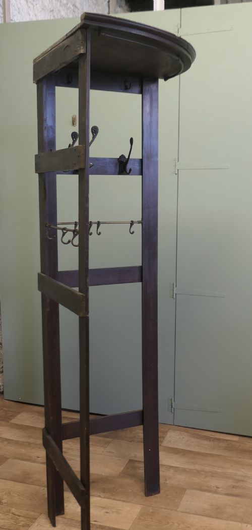 fig 1. A tall dark brown wooden corner coat stand featuring a curved top shelf, hinged folding side panels, and metal hanging hooks.