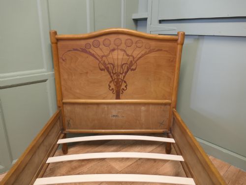 fig 1. An antique Vienna Secession single wooden bedstead featuring arched headboard and footboard panels decorated with stylised botanical marquetry motifs.