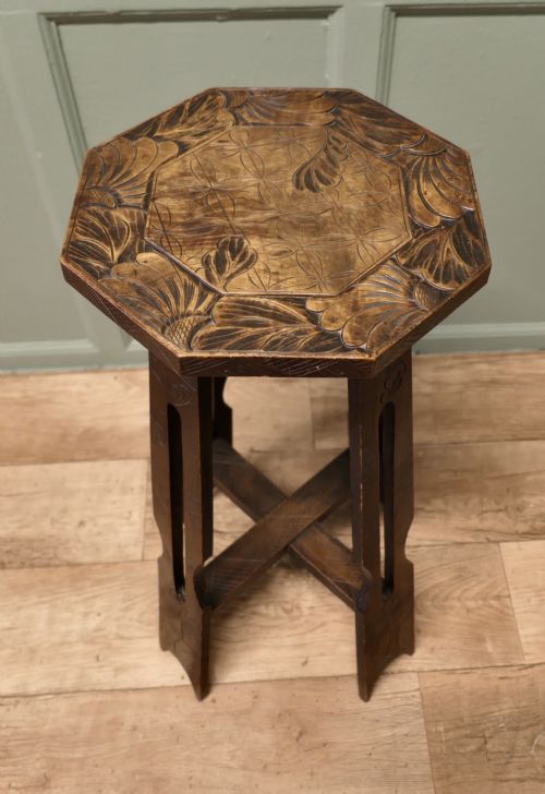 fig 1. An Arts and Crafts dark elm plant stand featuring an octagonal carved top, stylised floral carving on four pierced legs, and an X-frame stretcher.