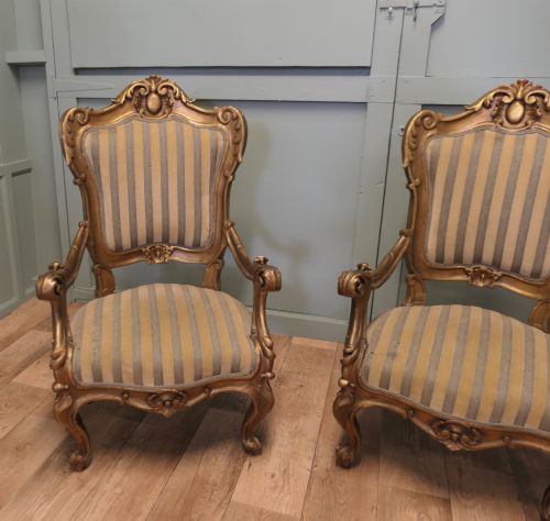 fig 1. A pair of ornate Italian Rococo style armchairs with carved giltwood frames and grey and gold striped upholstery.
