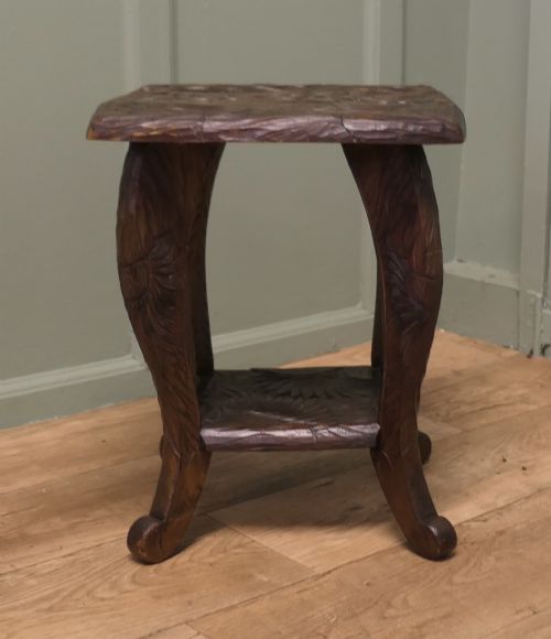 fig 1. A square dark oak Arts and Crafts side table featuring hand-carved sunflower motifs across the top and lower shelf, supported by four gently curved legs.