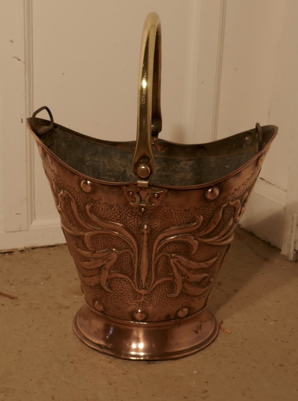 An Art Nouveau Embossed Copper Helmet Coal Scuttle with Liner