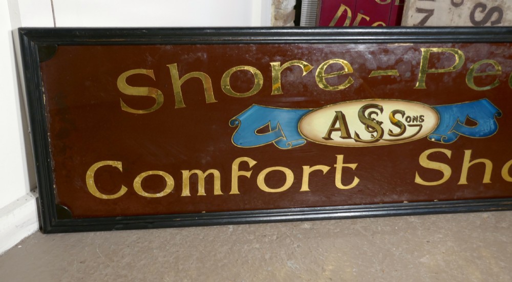 A wide rectangular black-framed commercial glass sign with gold leaf text reading Shore-Pedic Comfort Shoes on a dark brown background. View VI