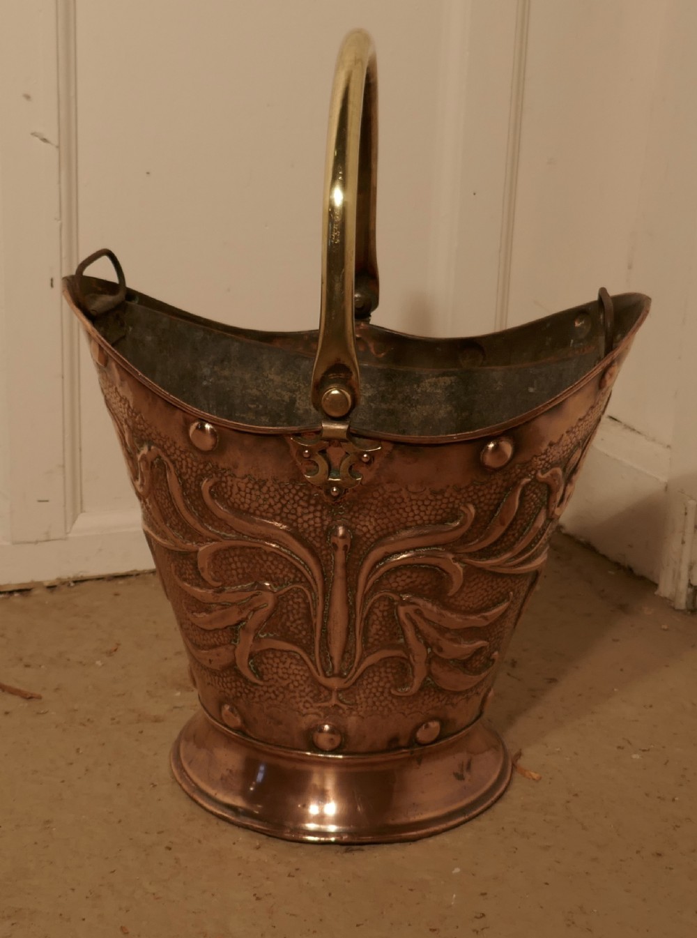 An Art Nouveau Embossed Copper Helmet Coal Scuttle with Liner