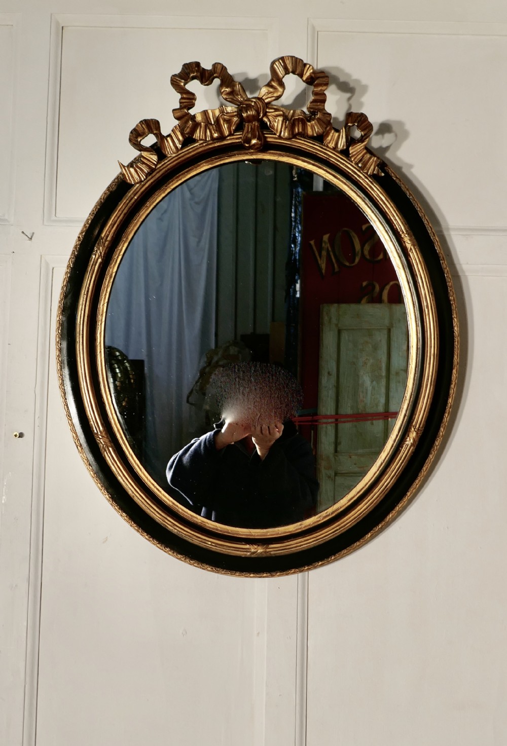 A Large French Ebonised and Gilt Oval Wall Mirror