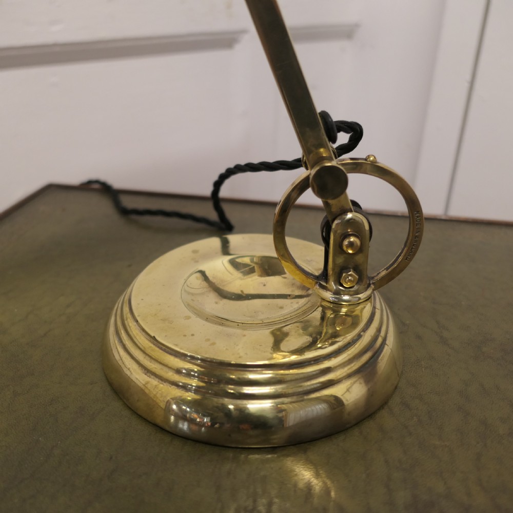 An Art Deco brass desk lamp featuring a curved metal shade, pull-chain switch, adjustable joint arm, and stepped circular base. View VII