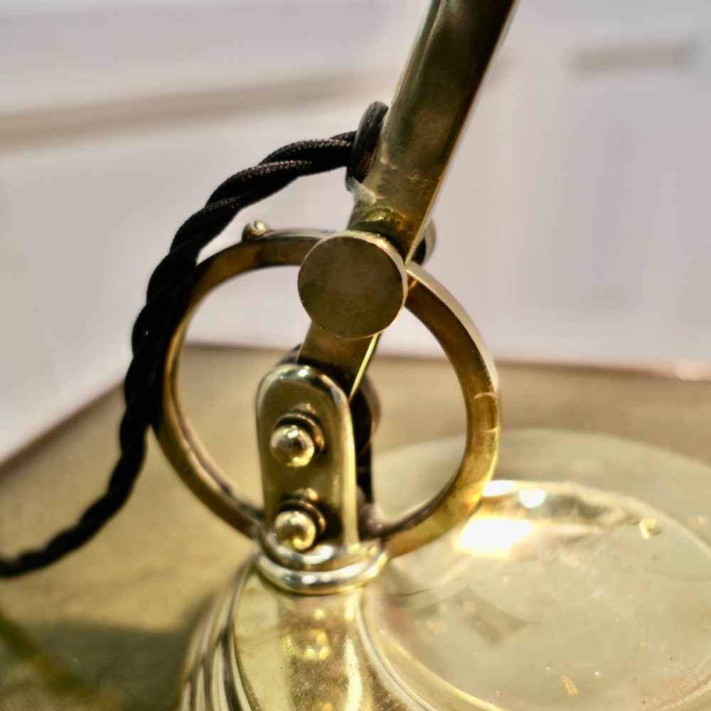 An Art Deco brass desk lamp featuring a curved metal shade, pull-chain switch, adjustable joint arm, and stepped circular base. View VIII