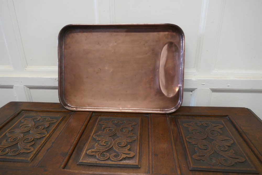 A large rectangular copper roasting tray featuring rolled rims and an indented oval gravy well at one end. View V