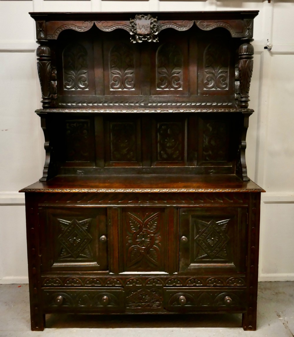 An 18th-century carved dark oak Welsh dresser featuring an upper open plate rack with carved panels above a lower cabinet base with drawers and doors. View II