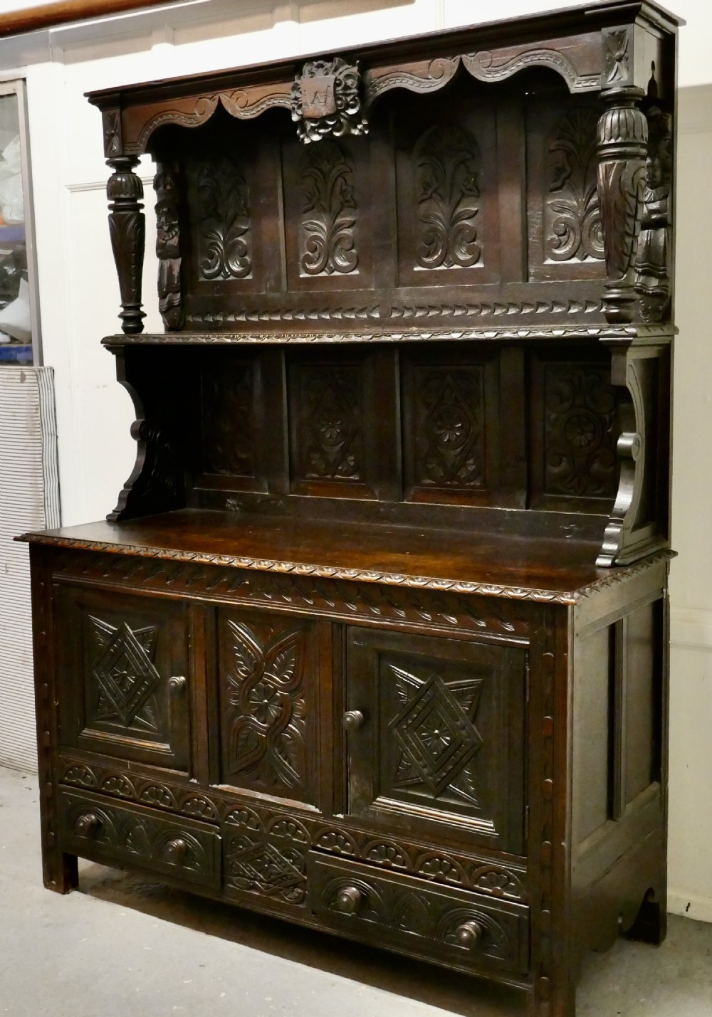 An 18th-century carved dark oak Welsh dresser featuring an upper open plate rack with carved panels above a lower cabinet base with drawers and doors. View III