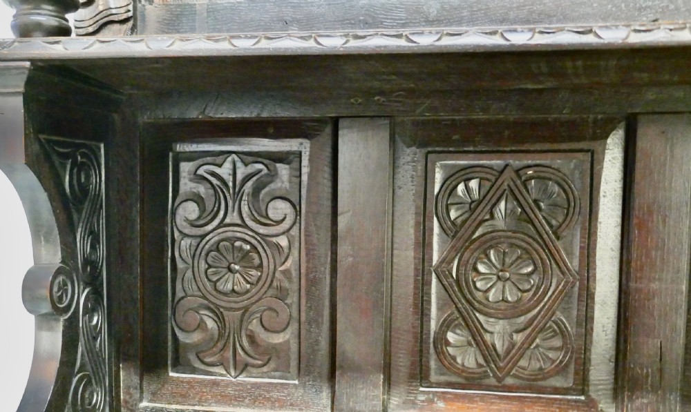 An 18th-century carved dark oak Welsh dresser featuring an upper open plate rack with carved panels above a lower cabinet base with drawers and doors. View XI