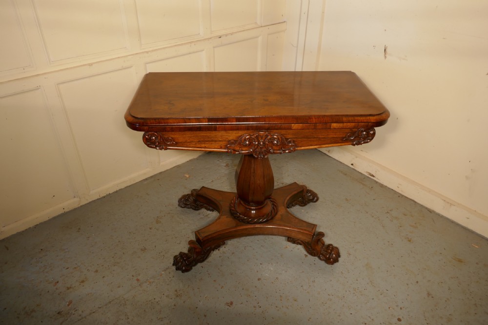 A William IV dark wood folding card table featuring a carved frieze, central turned pedestal, and a concave quadform plinth base with scroll feet. View III