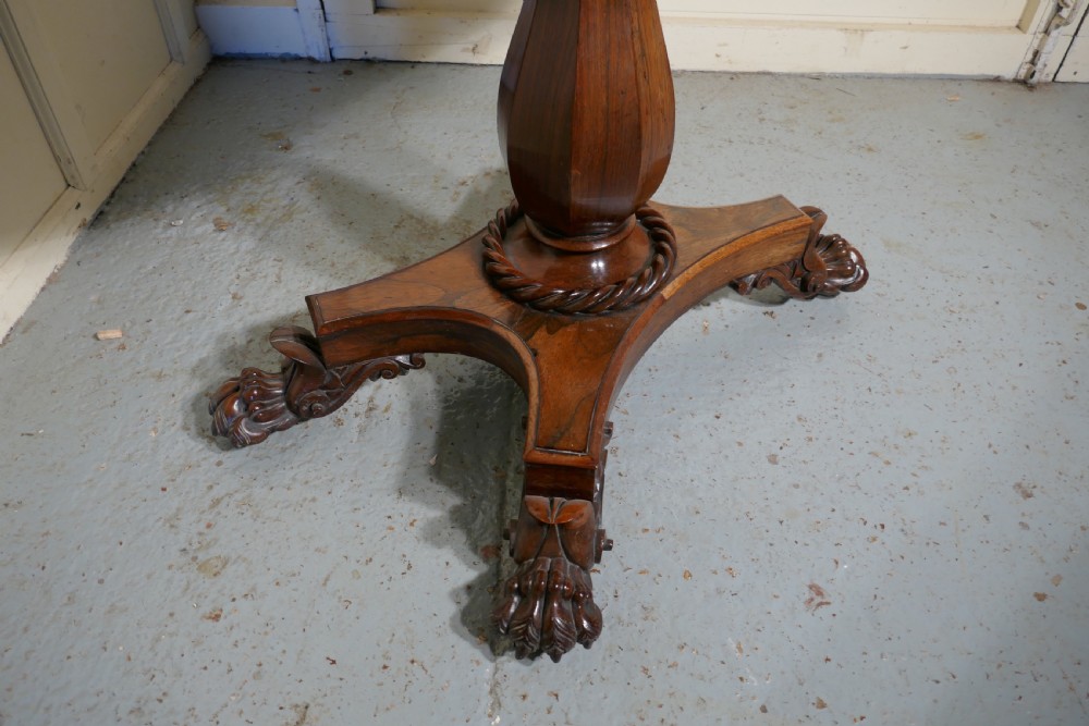 A William IV dark wood folding card table featuring a carved frieze, central turned pedestal, and a concave quadform plinth base with scroll feet. View VI