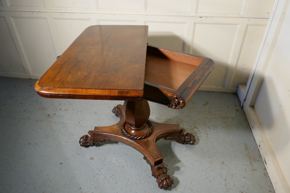 A William IV dark wood folding card table featuring a carved frieze, central turned pedestal, and a concave quadform plinth base with scroll feet. View VII