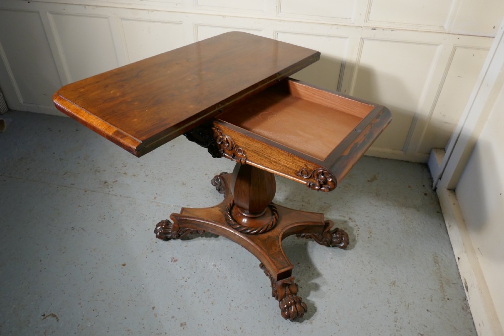 A William IV dark wood folding card table featuring a carved frieze, central turned pedestal, and a concave quadform plinth base with scroll feet. View VIII