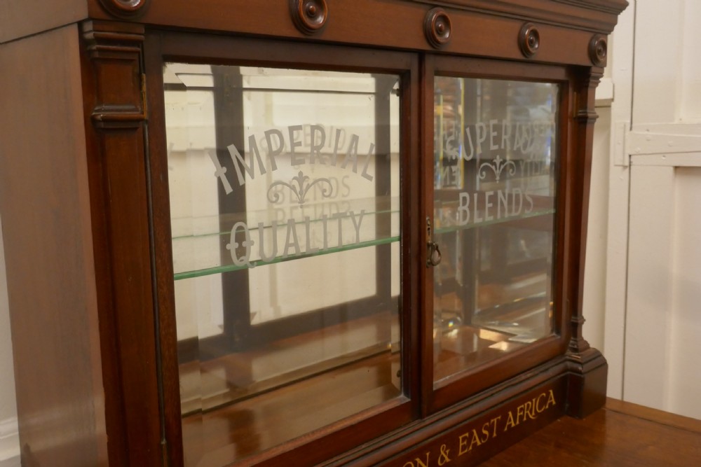 A Victorian mahogany shop counter display cabinet with etched glass doors, mirror backing, and gold lettering reading Teas of the Empire. View V