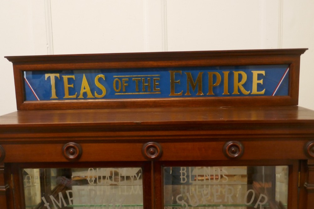 A Victorian mahogany shop counter display cabinet with etched glass doors, mirror backing, and gold lettering reading Teas of the Empire. View VI