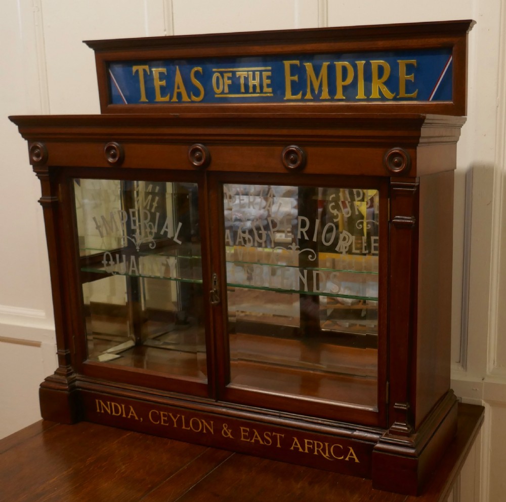 A Victorian mahogany shop counter display cabinet with etched glass doors, mirror backing, and gold lettering reading Teas of the Empire. View VII