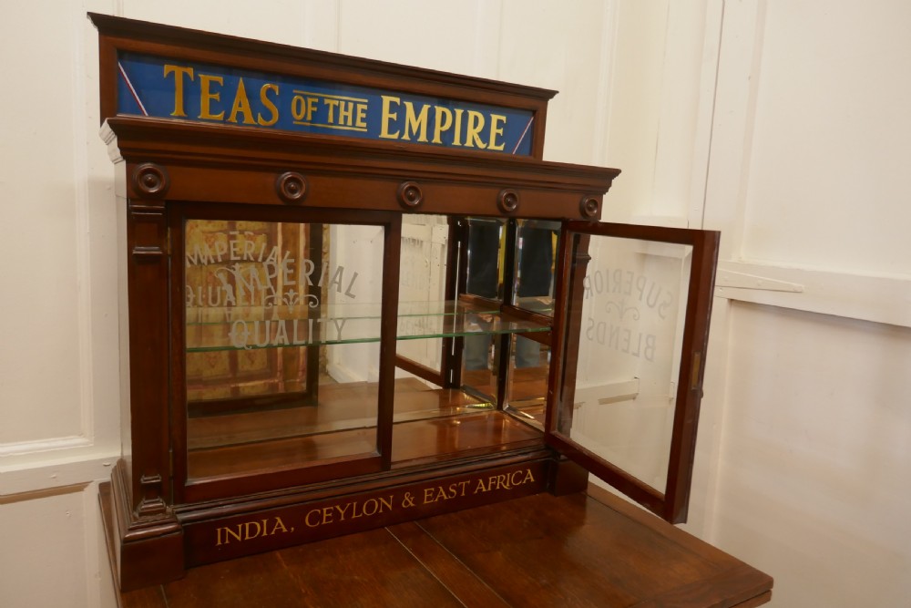 A Victorian mahogany shop counter display cabinet with etched glass doors, mirror backing, and gold lettering reading Teas of the Empire. View VIII