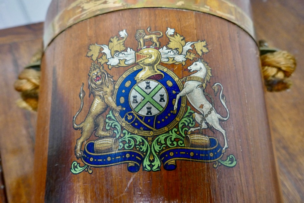 A 19th-century dark oak fire bucket featuring brass binding, a thick rope handle covered in brown leather, and a painted Plymouth armorial crest on the front. View IV