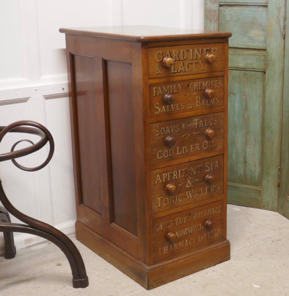 A tall Victorian pine chest featuring five drawers with turned wooden knobs and hand-painted gilt pharmacy lettering across each drawer front. View IX