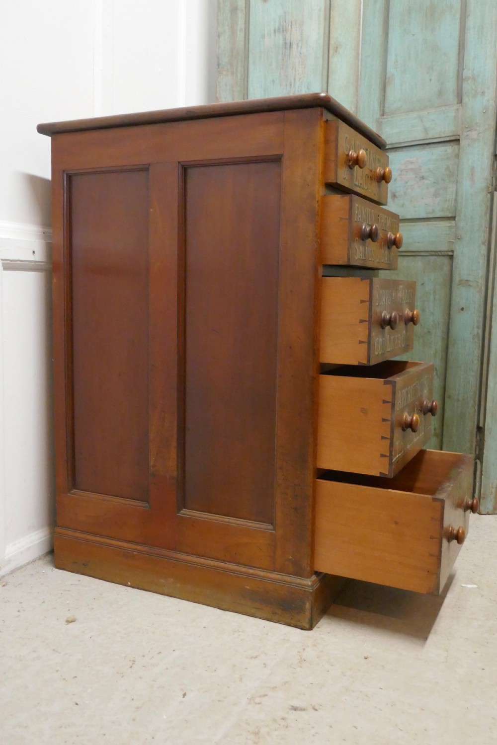 A tall Victorian pine chest featuring five drawers with turned wooden knobs and hand-painted gilt pharmacy lettering across each drawer front. View XIII