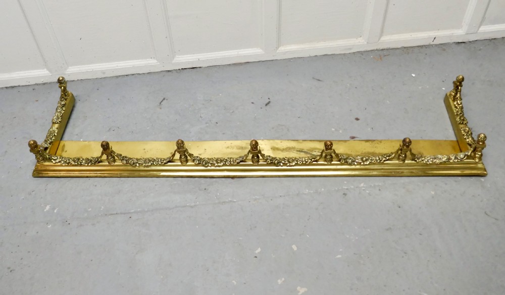 A 19th-century brass fireplace fender curb featuring baluster posts with pinecone finials and cast brass floral garlands. View II