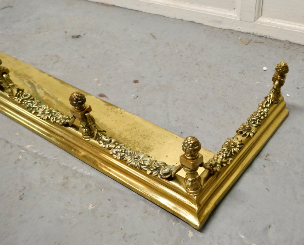 A 19th-century brass fireplace fender curb featuring baluster posts with pinecone finials and cast brass floral garlands. View IV