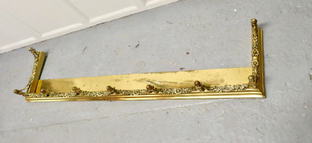 A 19th-century brass fireplace fender curb featuring baluster posts with pinecone finials and cast brass floral garlands. View V