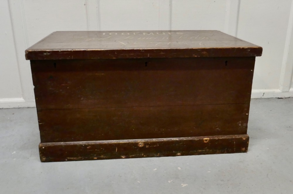 A 19th-century dark stained pine lodge chest featuring white painted lettering on the hinged top lid and a solid plinth base.