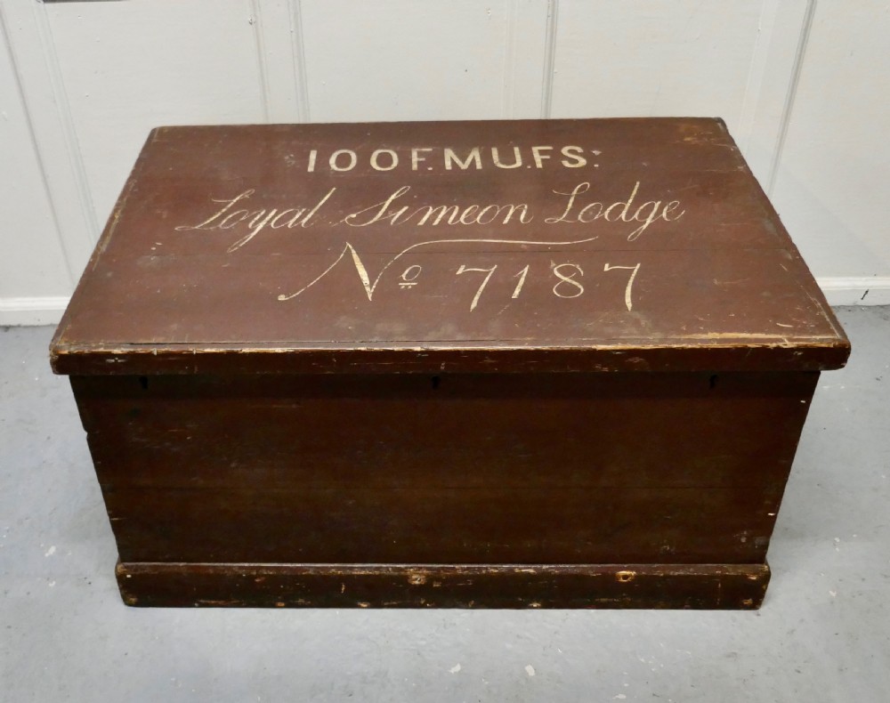 A 19th-century dark stained pine lodge chest featuring white painted lettering on the hinged top lid and a solid plinth base. View II